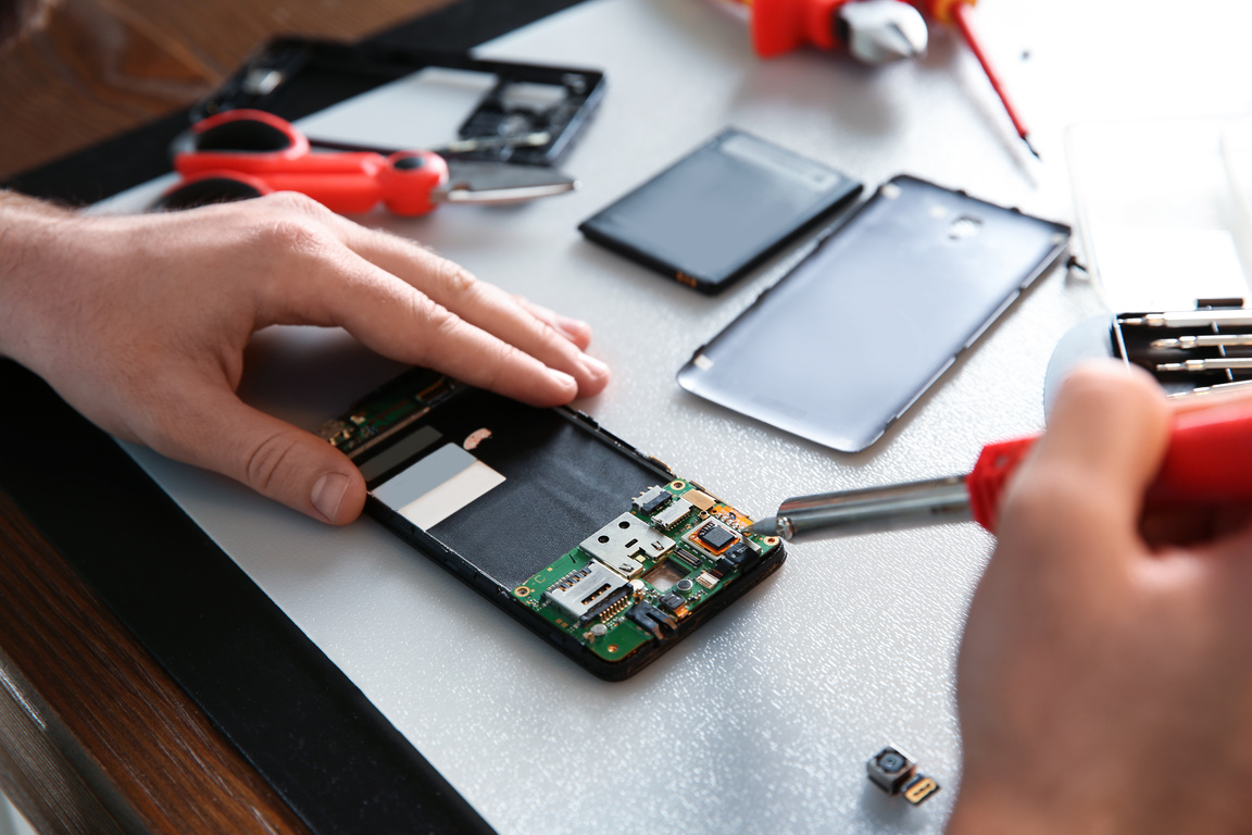 Technician Repairing Mobile Phone at Table, Closeup